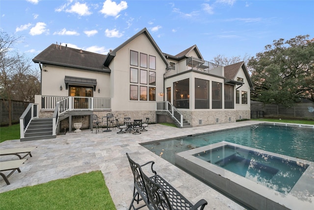 rear view of house with a pool with hot tub, a patio area, and a balcony