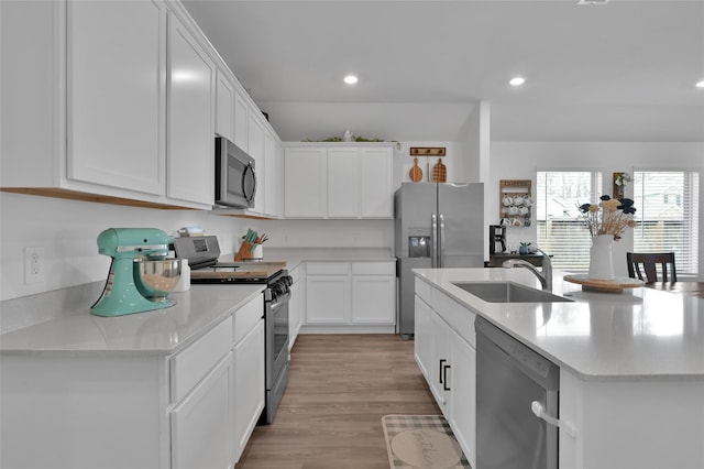 kitchen featuring sink, light hardwood / wood-style flooring, white cabinetry, a kitchen island with sink, and stainless steel appliances