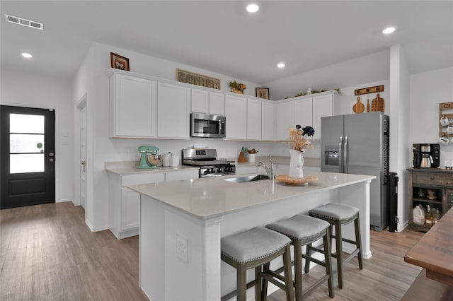 kitchen featuring sink, appliances with stainless steel finishes, a kitchen breakfast bar, an island with sink, and white cabinets