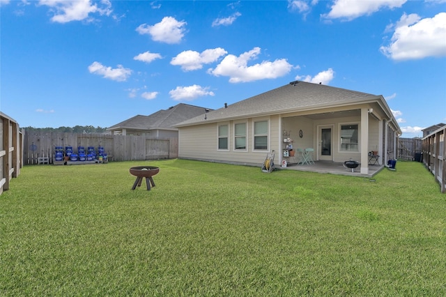 back of property with a lawn, a patio, and an outdoor fire pit