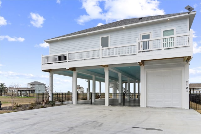 rear view of house with a carport, concrete driveway, and fence