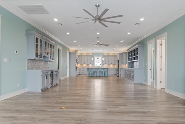 unfurnished living room with ornamental molding, ceiling fan, and light wood-type flooring