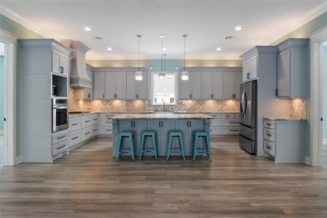 kitchen with custom exhaust hood, a kitchen island, stainless steel appliances, and crown molding