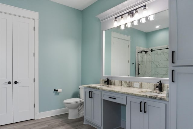 bathroom with vanity, tiled shower, hardwood / wood-style floors, and toilet