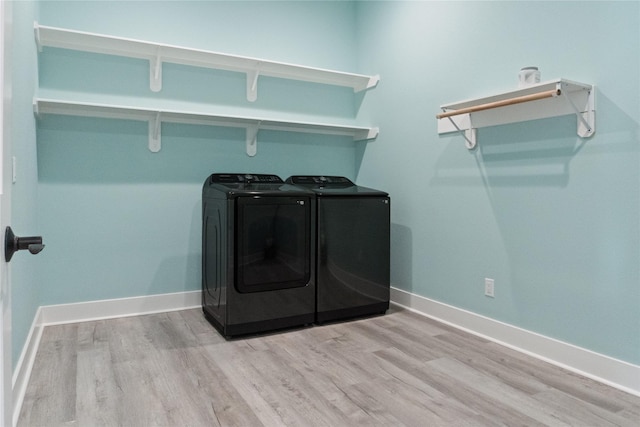 clothes washing area featuring light hardwood / wood-style floors and washing machine and dryer