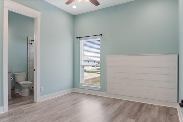 unfurnished bedroom featuring a ceiling fan, wood finished floors, baseboards, and connected bathroom