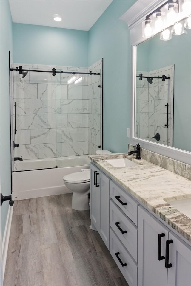 full bathroom featuring vanity, hardwood / wood-style flooring, toilet, and tiled shower / bath combo