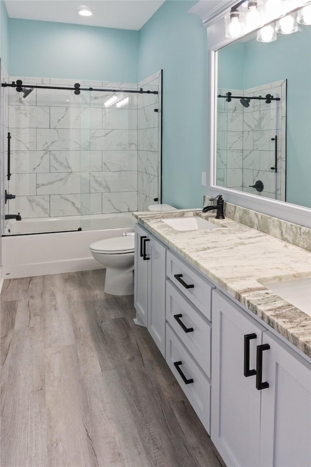 full bathroom featuring hardwood / wood-style flooring, tiled shower / bath, vanity, and toilet