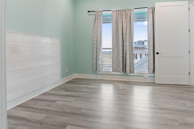 unfurnished room with a wealth of natural light, baseboards, and wood finished floors