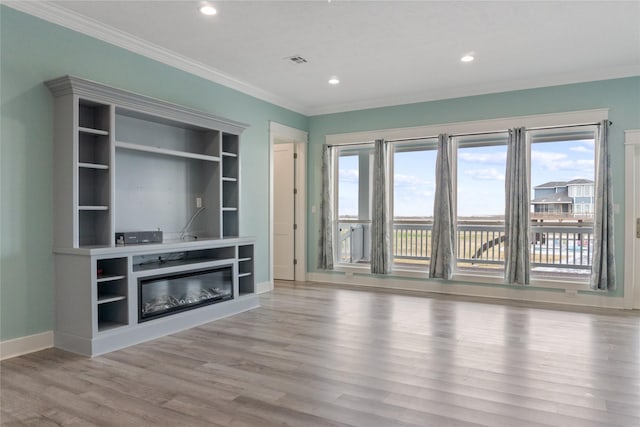 unfurnished living room with visible vents, ornamental molding, recessed lighting, wood finished floors, and a glass covered fireplace