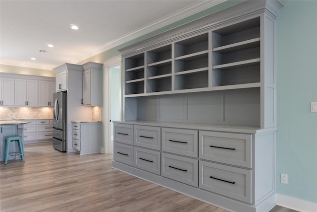 kitchen featuring tasteful backsplash, white cabinets, light hardwood / wood-style floors, stainless steel fridge with ice dispenser, and crown molding