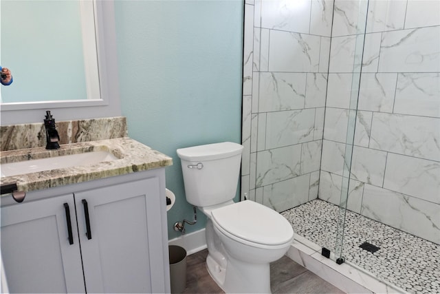 full bathroom featuring toilet, a stall shower, wood finished floors, baseboards, and vanity