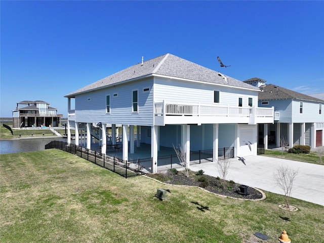 back of property featuring a shingled roof, concrete driveway, a lawn, a carport, and a patio