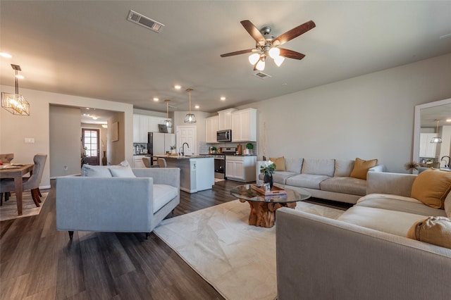 living room featuring dark wood-type flooring, sink, and ceiling fan