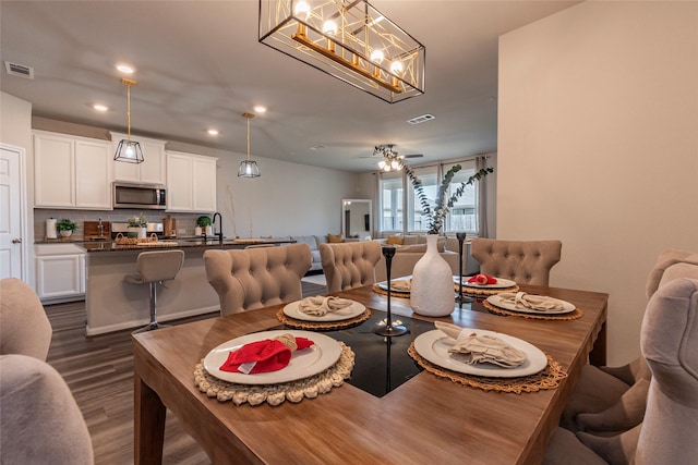 dining space with ceiling fan with notable chandelier, dark hardwood / wood-style flooring, and sink