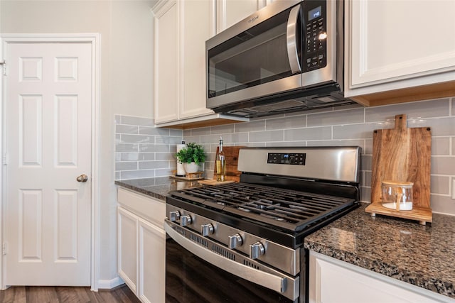 kitchen featuring stainless steel appliances, dark stone countertops, and white cabinets