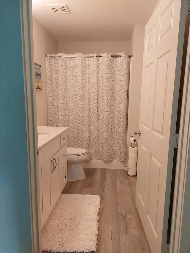 bathroom with wood-type flooring, toilet, and vanity