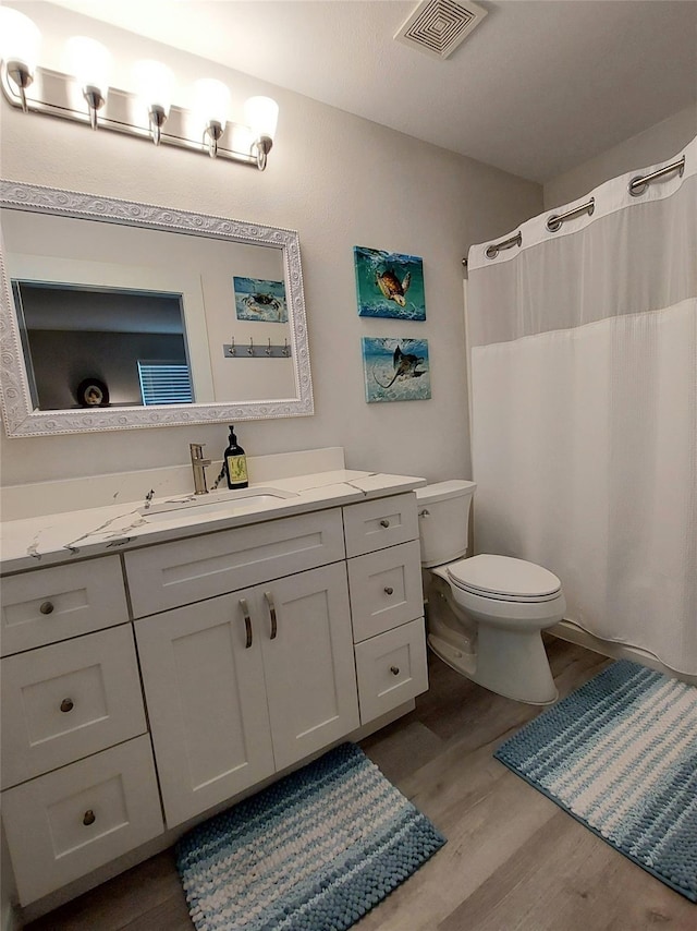 bathroom featuring wood-type flooring, vanity, and toilet