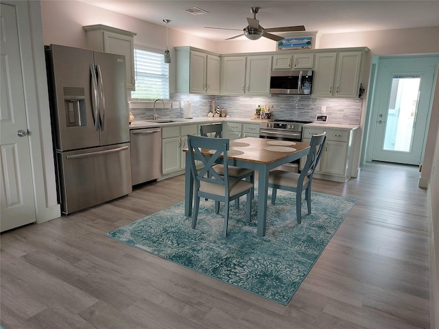 kitchen with sink, decorative backsplash, light wood-type flooring, and appliances with stainless steel finishes