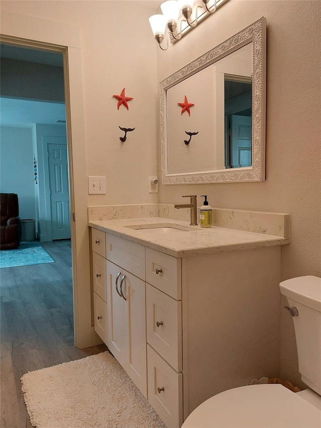 bathroom with vanity, hardwood / wood-style floors, toilet, and an inviting chandelier