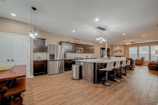 kitchen with stainless steel appliances, an island with sink, a breakfast bar, and pendant lighting