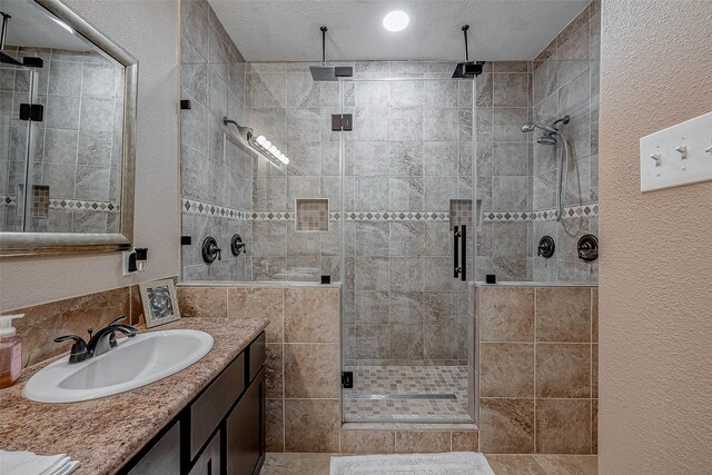 bathroom with vanity, an enclosed shower, and a textured ceiling