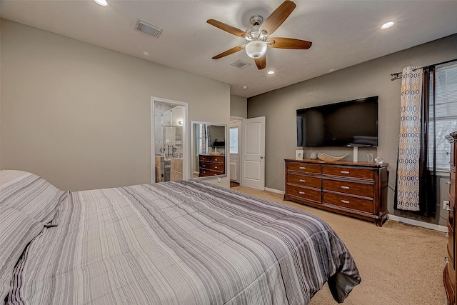 bedroom with ceiling fan, light colored carpet, and ensuite bath