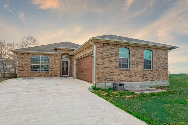 view of front facade featuring a garage, a yard, concrete driveway, and brick siding