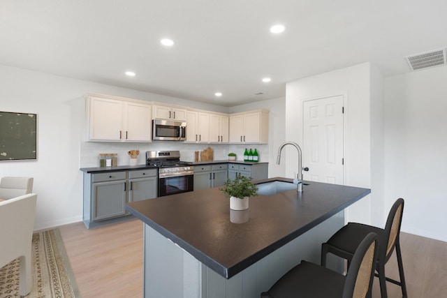 kitchen featuring stainless steel appliances, gray cabinets, sink, and light hardwood / wood-style flooring