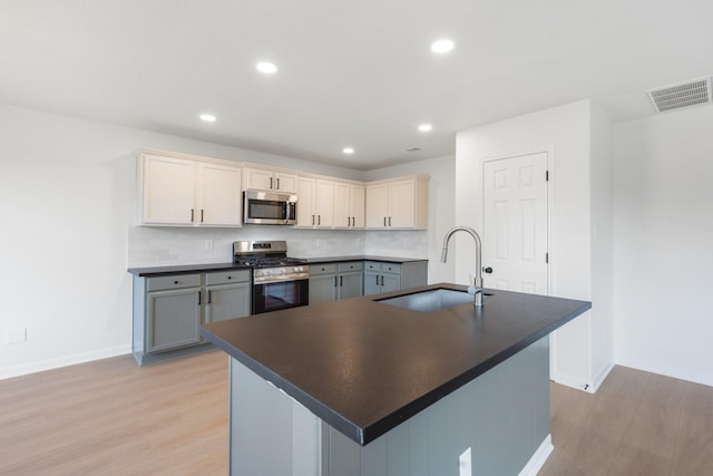 kitchen featuring sink, light hardwood / wood-style flooring, gray cabinetry, stainless steel appliances, and tasteful backsplash