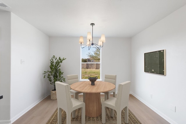 dining area with a chandelier and light hardwood / wood-style flooring