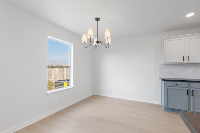 unfurnished dining area featuring a notable chandelier and light wood-type flooring