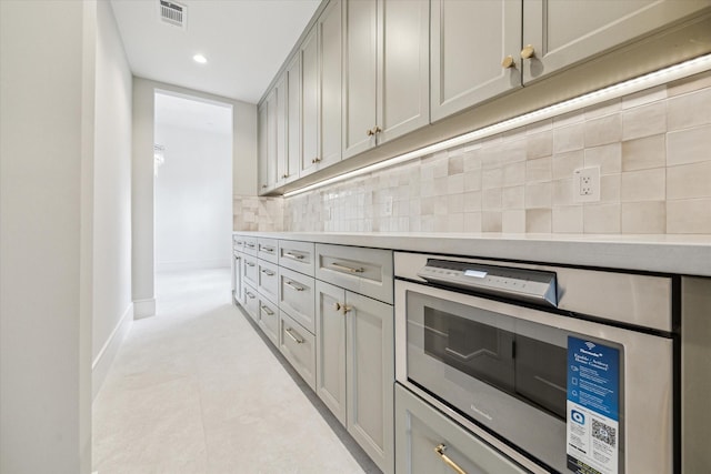 kitchen with tasteful backsplash, recessed lighting, light countertops, visible vents, and gray cabinetry