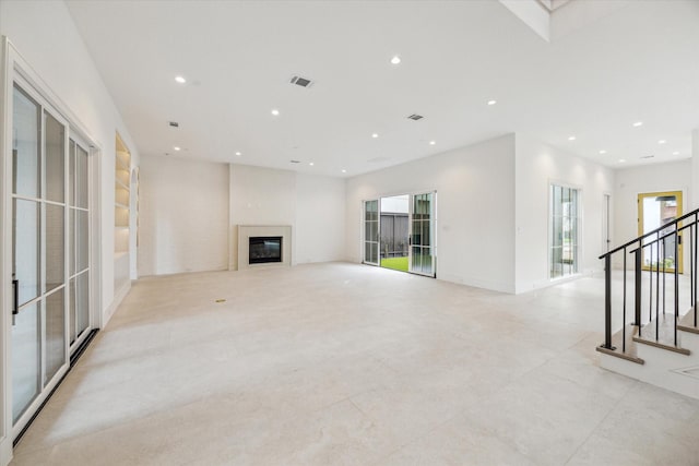 unfurnished living room with stairway, recessed lighting, visible vents, and a glass covered fireplace