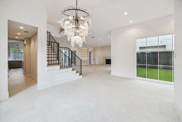 unfurnished living room with visible vents, baseboards, stairway, an inviting chandelier, and recessed lighting