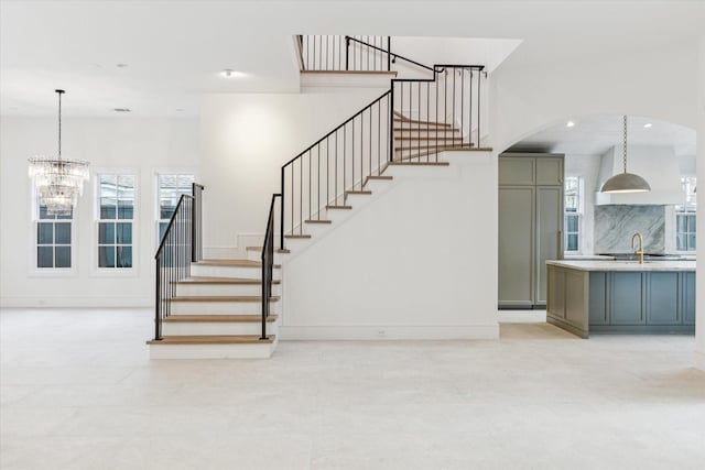 staircase featuring an inviting chandelier, baseboards, and recessed lighting