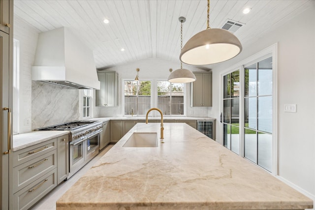 kitchen featuring a center island with sink, custom range hood, hanging light fixtures, gray cabinets, and a sink