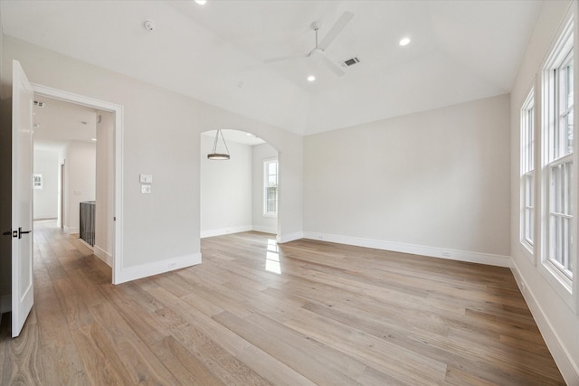 empty room featuring arched walkways, recessed lighting, light wood-style flooring, ceiling fan, and baseboards