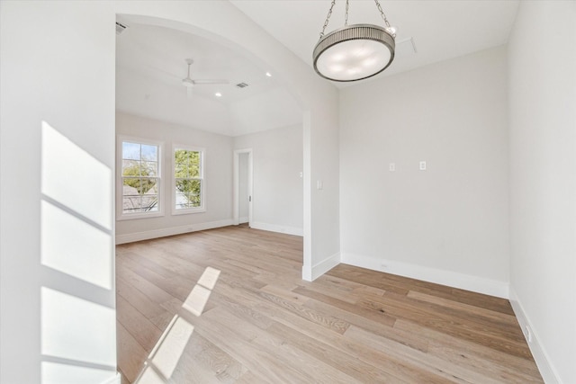 spare room featuring ceiling fan, light wood-type flooring, arched walkways, and baseboards