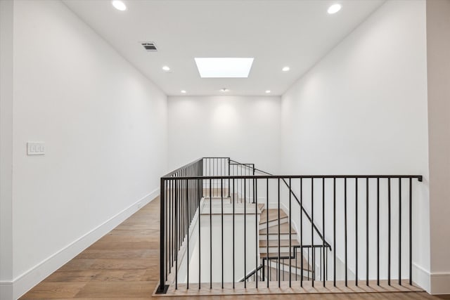 corridor with a skylight, visible vents, baseboards, light wood-style flooring, and recessed lighting