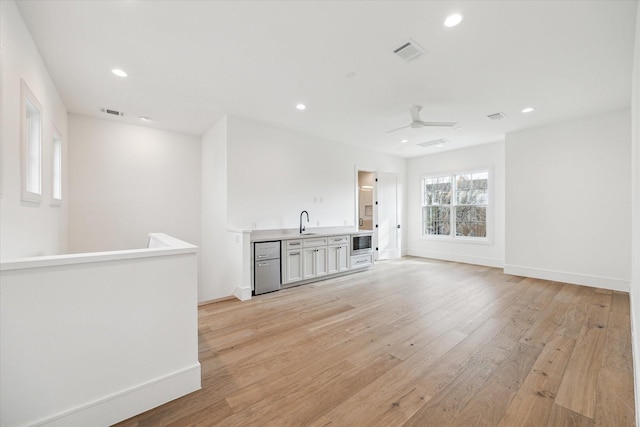 bar featuring light wood-style flooring, visible vents, a sink, and recessed lighting