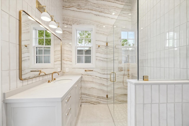 bathroom with vanity, a marble finish shower, and tile walls