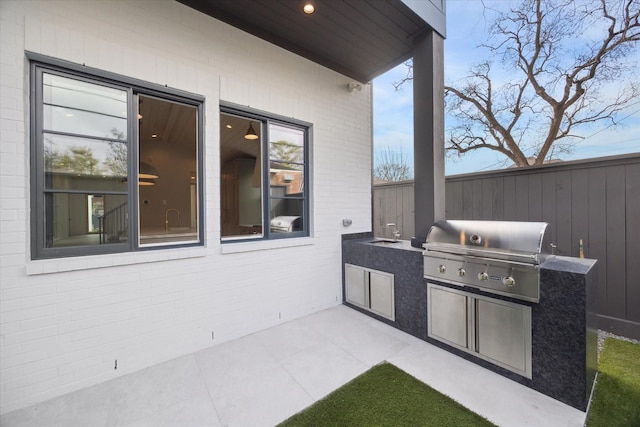 view of patio / terrace with grilling area, an outdoor kitchen, and fence