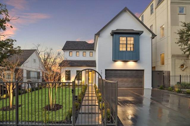 view of front facade featuring a fenced front yard, a lawn, a gate, a garage, and driveway