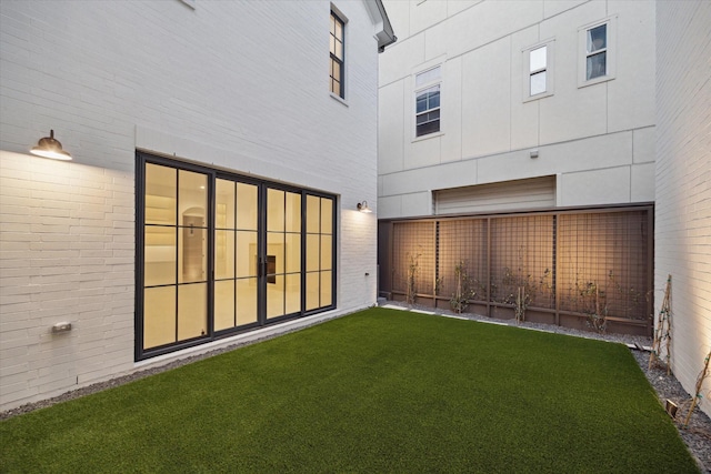 rear view of house featuring a lawn and brick siding