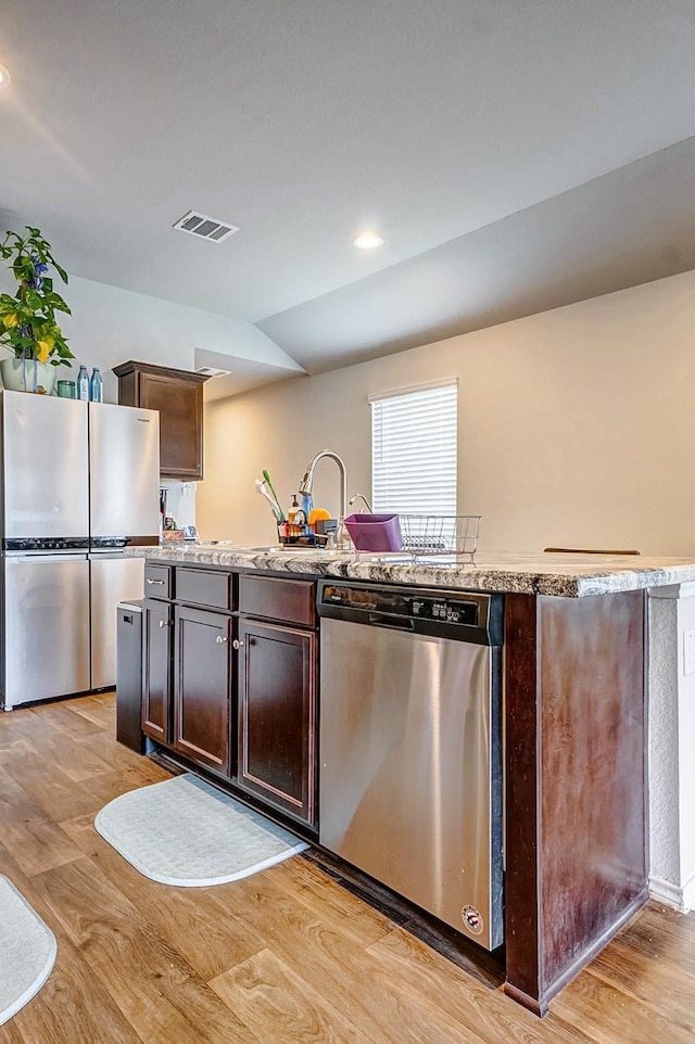 kitchen featuring dark brown cabinetry, stainless steel appliances, light hardwood / wood-style floors, and lofted ceiling