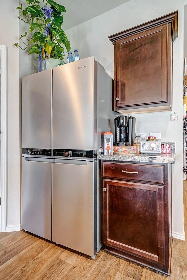 kitchen with stainless steel fridge, dark brown cabinets, and light wood-type flooring