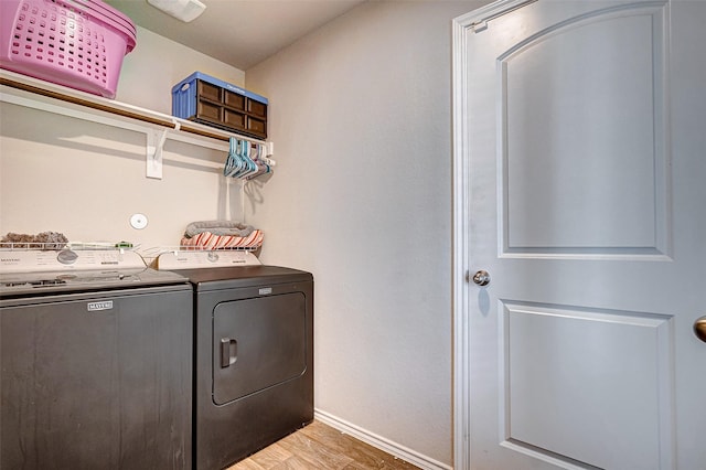 clothes washing area featuring washing machine and dryer and light wood-type flooring