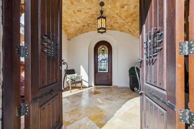 foyer entrance featuring lofted ceiling and brick ceiling