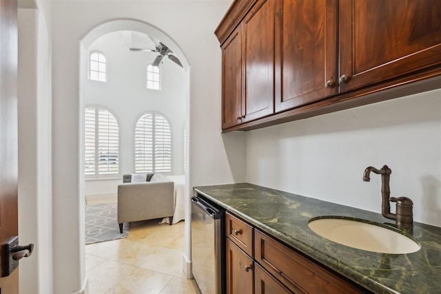 kitchen with ceiling fan, dark stone counters, sink, and light tile patterned floors